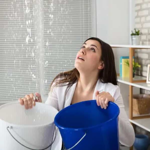 Femme en attente d'un plombier sanitaire car elle a un dégât d'eau venant du plafond. Elle tient du saut