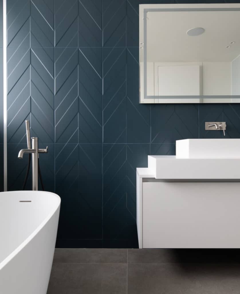 Salle de bain haut de gamme avec baignoire et lavabo de couleur blanche et carrelage bleu en chevron
